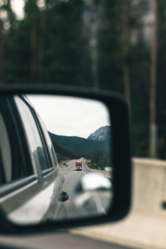 Captured highway view in a car mirror, showcasing travel and reflection.
